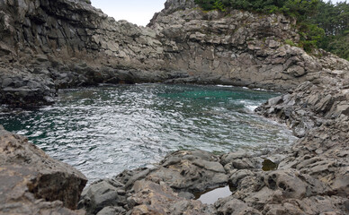 Volcanic rocks and clear sea water at Hwangwooji Seonnyeotang near Seogwipo-si, Jeju-do, South Korea