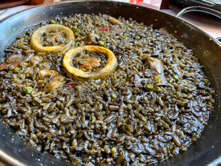 black rice paella with squid, mussels, spain