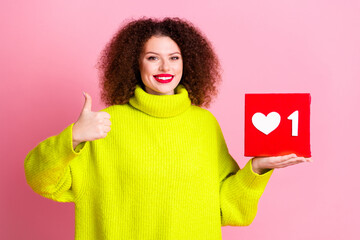Photo portrait of lovely young lady hold heart icon thumb up dressed stylish yellow garment isolated on pink color background