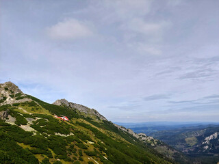Fototapeta premium Red rescue helicopter is flying over green Gievont mountain slopes in tatra national park, poland