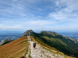 Hikers enjoying the view while walking on a mountain ridge hiking trail in tatra national park, Giewont, Tatra national park, Poland