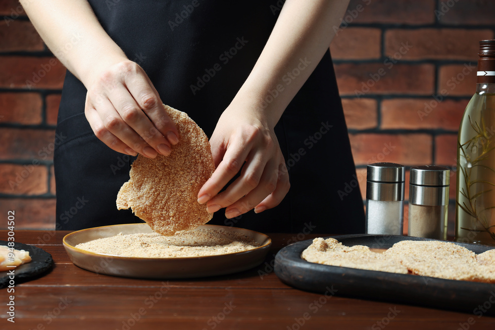 Canvas Prints woman making schnitzel at wooden table, closeup