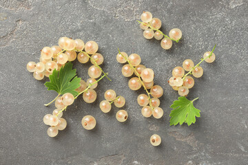 Fresh white currant berries and green leaves on gray textured table, flat lay