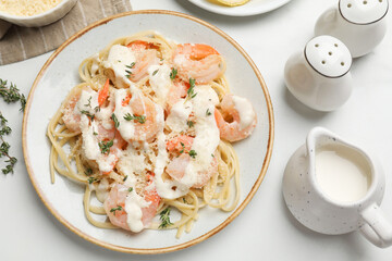 Tasty pasta with shrimps, creamy sauce and cheese served on white table, flat lay