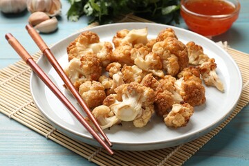 Baked cauliflower, products and sauce on light blue wooden table