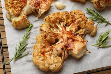 Tasty cauliflower steaks, rosemary and garlic on table, closeup