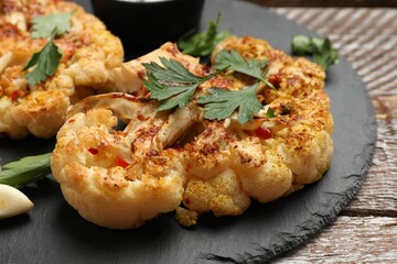 Delicious baked cauliflower steaks on wooden table, closeup