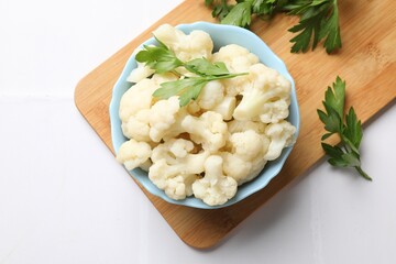 Tasty cauliflower with parsley on white tiled table, top view