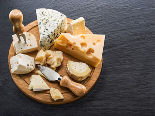 Cheese board with different cheeses on gray graphite table top view.