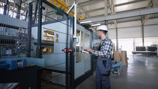 Engineer sets up a production line at programmable CNC machine in window factory