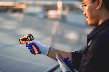 A man is holding a device that is orange and has a blue handle. He is wearing gloves and a hard hat