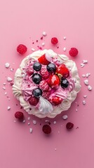 A pavlova dessert with fresh berries and whipped cream on a pink background.