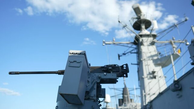 Color image of an automated machine gun on the deck of a military ship, at sea.