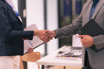 Businessmen shaking hands, greeting and working together, having documents with financial graphs and charts, brainstorming, close-up photo