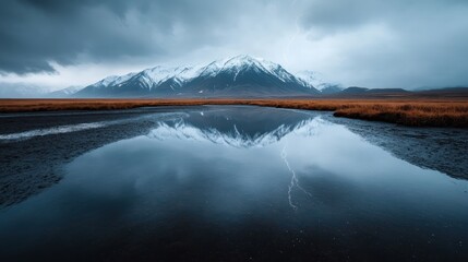 A serene lake perfectly mirrors the snowy mountains in the backdrop, framed by dramatic stormy clouds and a striking bolt of lightning cutting through the sky.
