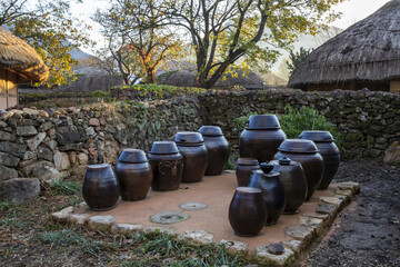 Suncheon-si, Jeollanam-do, South Korea - November 13, 2021: Autumnal and morning view of thatched houses with crocks besides stone wall at Nagan Eupseong Folk Village