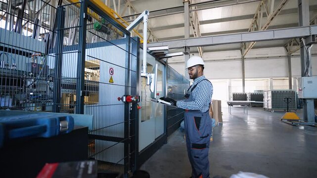 Indian engineer working at programmable CNC machine in factory industries