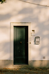 Green door on white wall with mailbox beside road