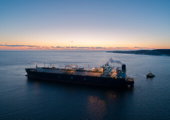 A large LNG tanker docks at an industrial port terminal for cargo operations at dusk