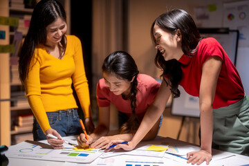 Group of asian businesswomen working late and brainstorming using sticky notes
