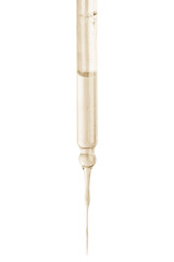 Cosmetic pipette with yellow liquid dripping. On a blank background. Acids, extract, serum, serum.
