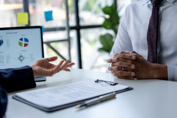 Two people are sitting at a table with a laptop and a piece of paper