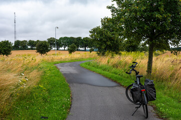 Trekking bike with paniers on a bending road at the Danish countryside around Vordingsborg,...