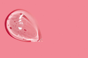 smear of clear gel on pink background with empty space.