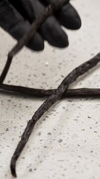 the cook's hand throws fresh vanilla pods on the table preparing ingredients for baking