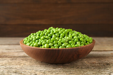 Fresh green peas in bowl on wooden table
