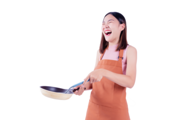 Cheerful young woman laughing while holding a frying pan, wearing an orange apron, captured against a white background. This image conveys a lighthearted and joyful moment in the kitchen.
