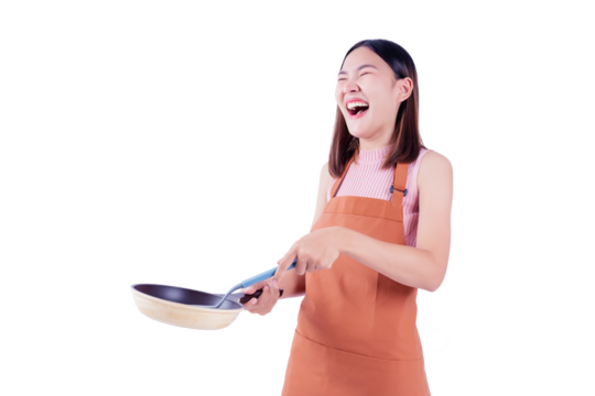 Cheerful young woman laughing while holding a frying pan, wearing an orange apron, captured against a white background. This image conveys a lighthearted and joyful moment in the kitchen. - Powered by Adobe