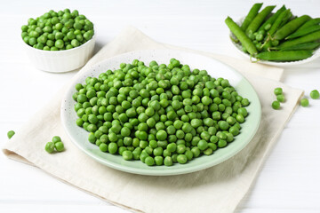 Fresh green peas and pods on white wooden table