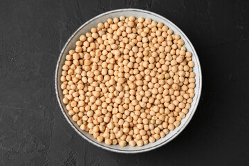 Dried peas in bowl on dark textured table, top view