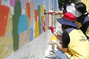 Sinbong-dong, Sangju-si, Gyeongsangbuk-do, South Korea - September 12, 2021: Volunteers are drawing mural on the wall of a house with brush © JinChang