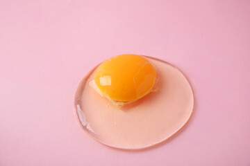 One raw egg on pink background, closeup