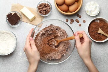 Woman making chocolate dough at light table, top view