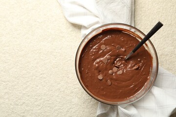 Melting chocolate chips for dough in bowl on light table, top view. Space for text