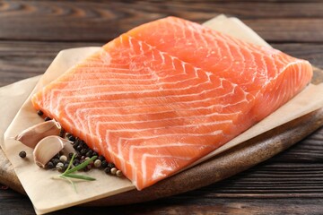 Piece of fresh salmon and spices on wooden table, closeup