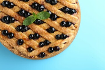 Delicious homemade blueberry pie with mint on light blue background, top view