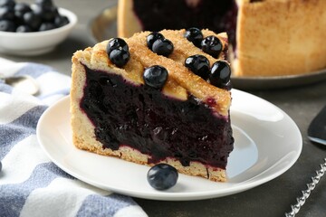 Slice of delicious homemade blueberry pie served on grey table, closeup