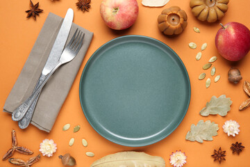 Beautiful table setting with autumn decor on orange background, flat lay