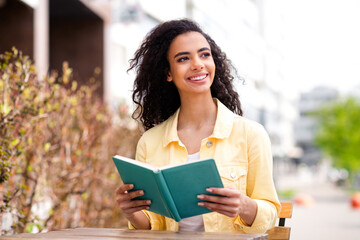 Portrait of lovely nice young girl read book look curious away city street cafe outdoors