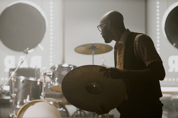 Young African American man getting ready for live performance setting drum kit