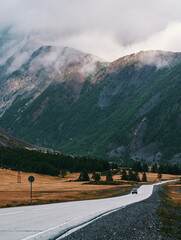 Majestic mountains under cloudy skies along a serene country road in autumn