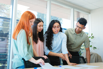 Young diverse professional team discussing and developing business strategies while standing around...