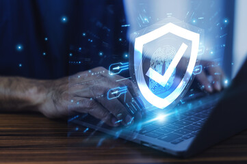 Man working on a laptop with advanced cyber security shield, ensuring the protection of sensitive data and securing the digital environment against potential threats.