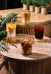 Four iced coffee drinks sitting on a cafe table in the sun