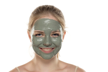 Beautiful young woman posing with a facial green mud mask on her face. Skin care and treatment, spa, natural beauty and cosmetology concept