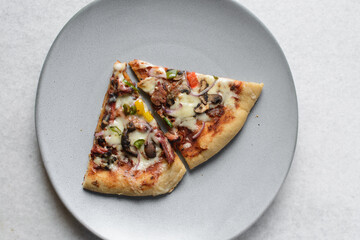Overhead view of chicken pizza slices on a grey plate, top view of beef and mushroom pizza slice